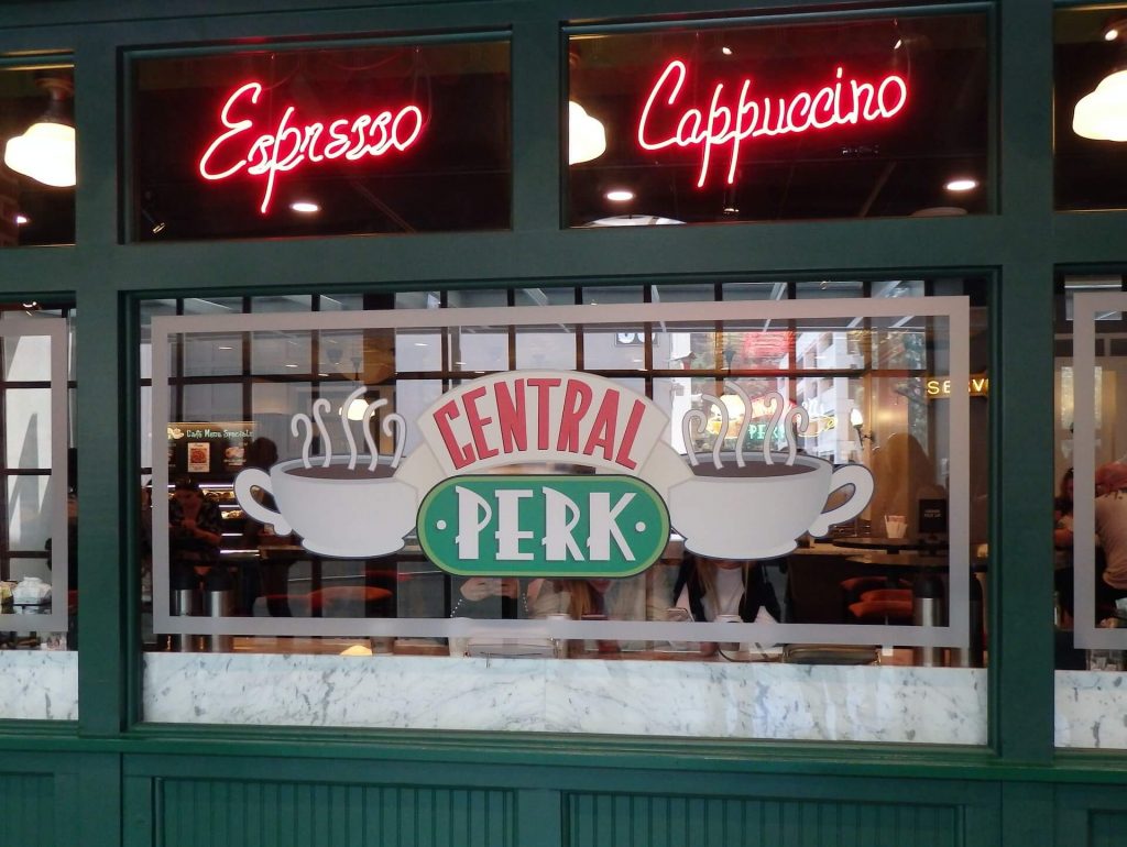 La icónica cafetería Central Perk de la serie de televisión Friends, con su familiar sofá naranja, sus tazas de café y su ambiente acogedor.